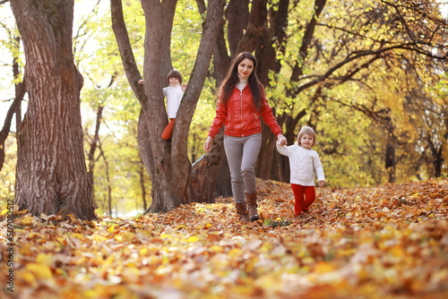 Young family on a walk in the autumn park on a sunny day. Happiness to be together.