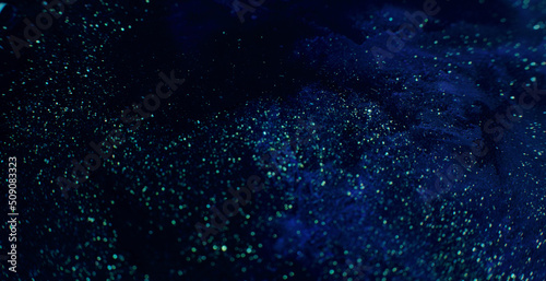 Glitter paint fluid. Volcano dust. Defocused golden sequin glow on dark blue liquid flow background shot on RED Cinema camera.