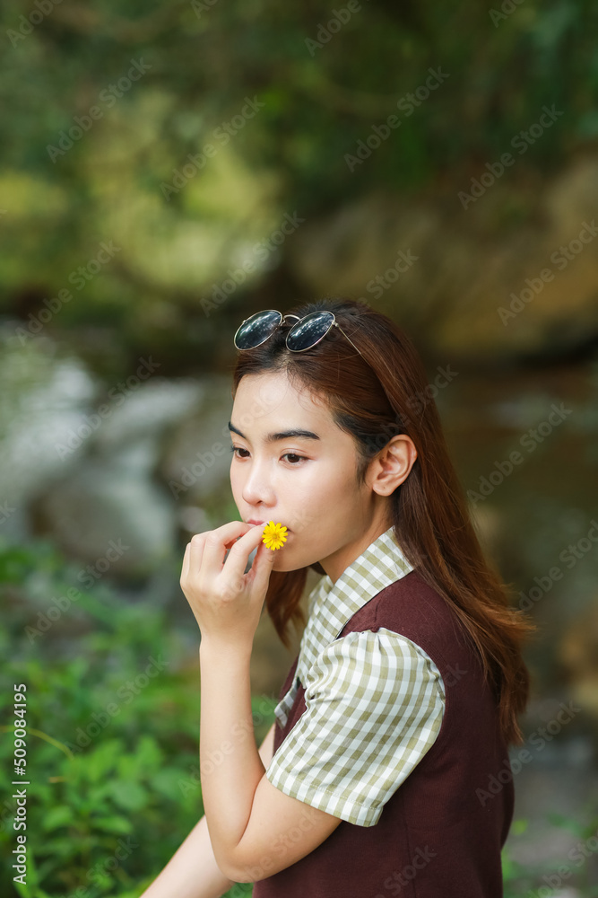 girl holding daisy flower covering her mouth, portrait of lady sitting with nature as background girl holding daisy flower covering her mouth, portrait of lady sitting with nature as background
