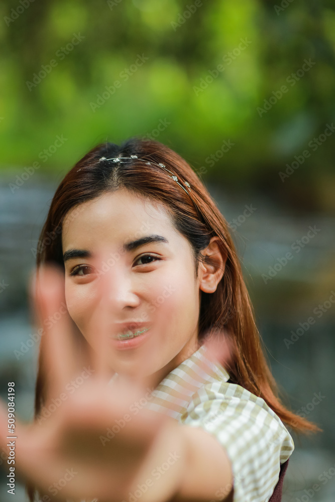Naklejka premium portrait of lady doing highfive,focus on girl's face,nature as background
