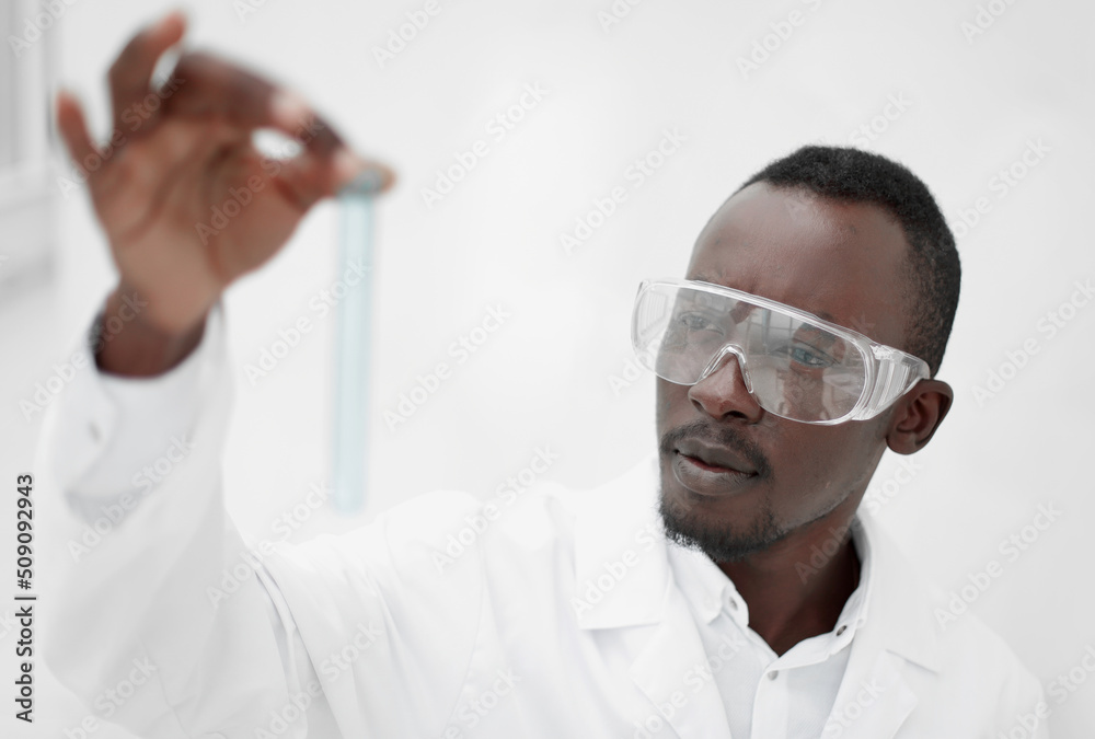 close up. Serious Clinician looking at flask with blue liquid close up. Serious Clinician looking at flask with blue liquid