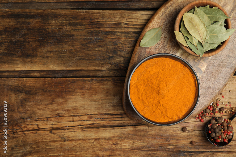 Bowl with saffron powder, peppercorns and bay leaves on wooden table, flat lay. Space for text Bowl with saffron powder, peppercorns and bay leaves on wooden table, flat lay. Space for text