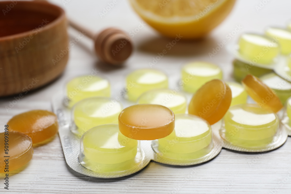 Many cough drops on white wooden table, closeup Many cough drops on white wooden table, closeup