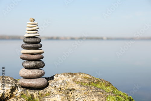 Stack of stones on rock near river  space for text. Harmony and balance concept