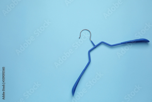 Empty clothes hanger on light blue background, top view. Space for text