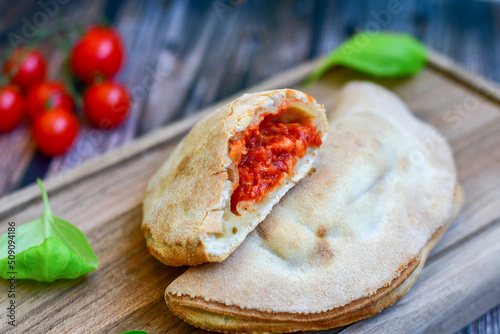 Home made italian calzone pizza with tomatoes, mozzarella and parmesan cheese and fresh basil 