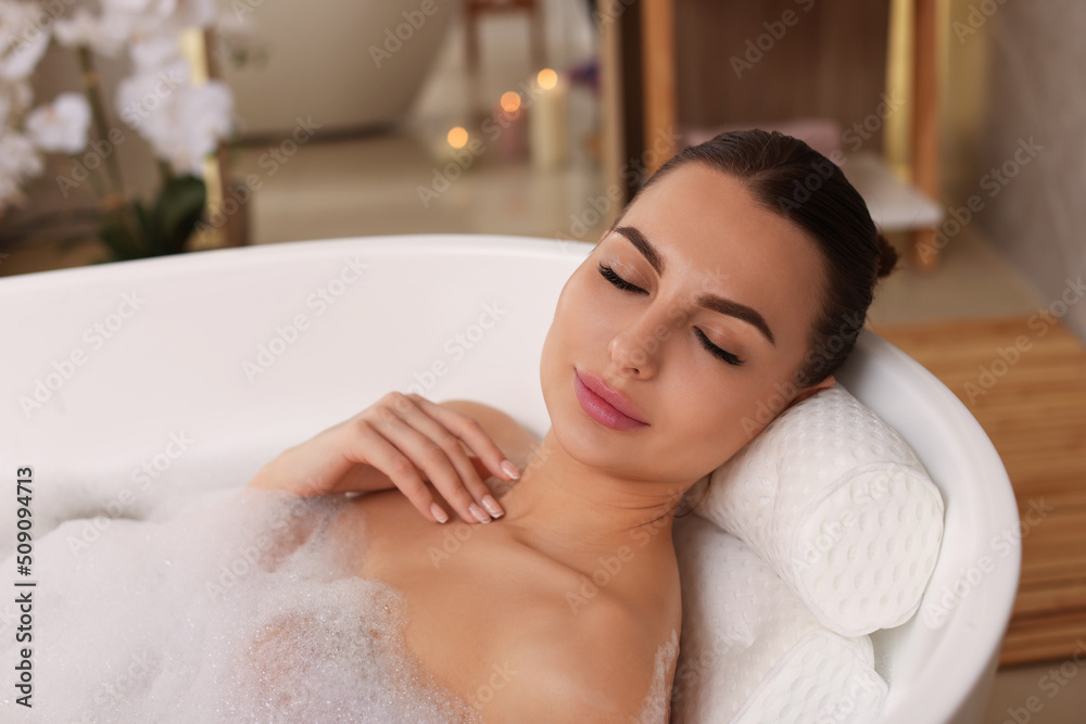 Young woman using pillow while enjoying bubble bath indoors Young woman using pillow while enjoying bubble bath indoors