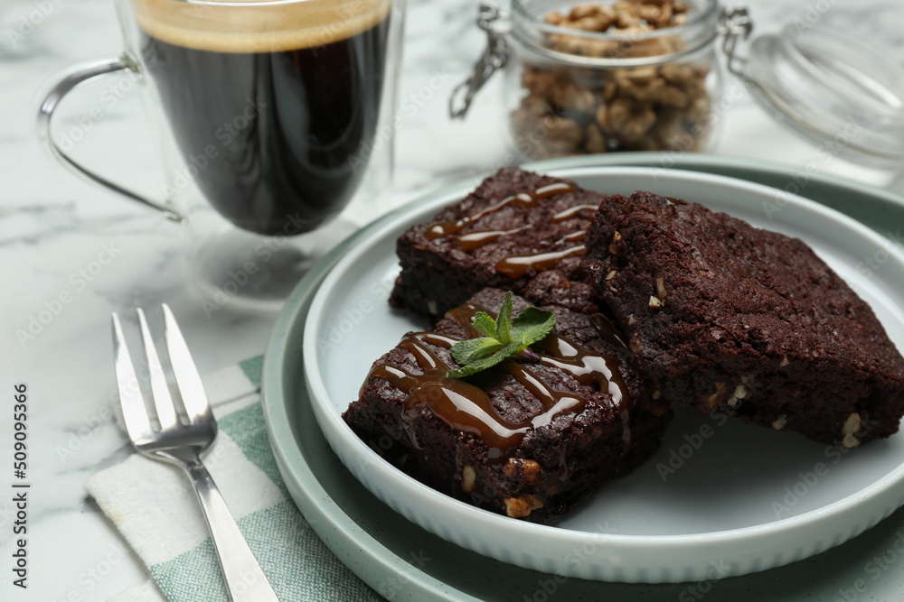 Delicious chocolate brownies with nuts, caramel sauce and fresh mint on white marble table, closeup Delicious chocolate brownies with nuts, caramel sauce and fresh mint on white marble table, closeup