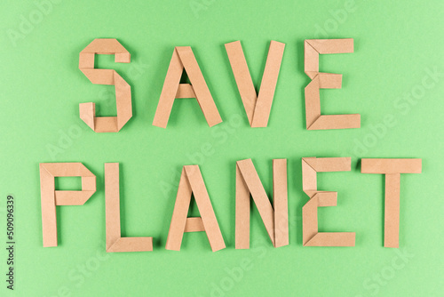 Fototapeta Naklejka Na Ścianę i Meble -  Sustainable lifestyle and zero waste concept. Text SAVE PLANET made with kraft paper letters, quote over green background. Ethical consumerism. Flat lay