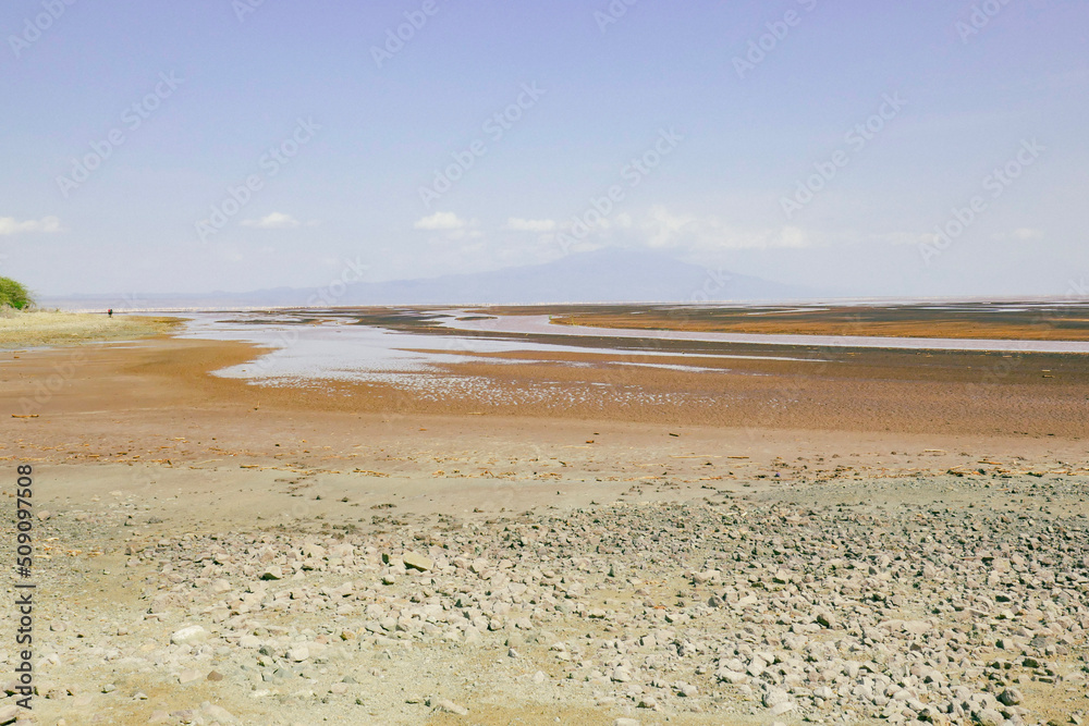 A tourist walking on the beach of Lake Natron on a sunny day in rural Tanzania