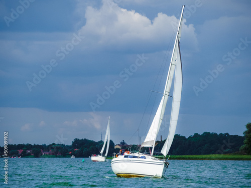 sailing yacht or sailboat on full sails swims on a lake in a windy day