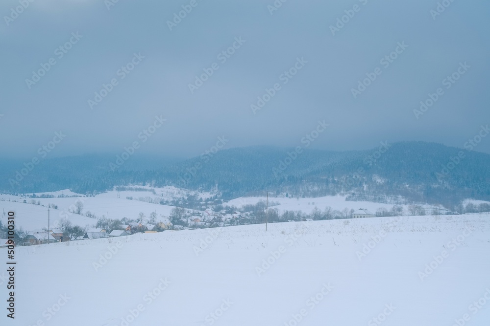 Snowing landscape in Europe. Lonely small village before the storm at mountains