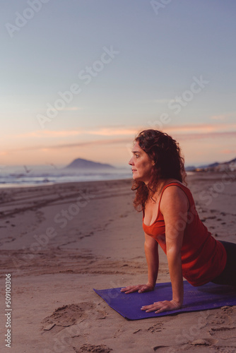 portrait of woman exercising on mat on beach © EvaHM