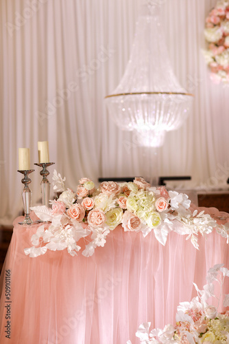 festive wedding table decoration with crystal chandeliers, golden candlesticks, candles and white pink flowers . stylish wedding day.
