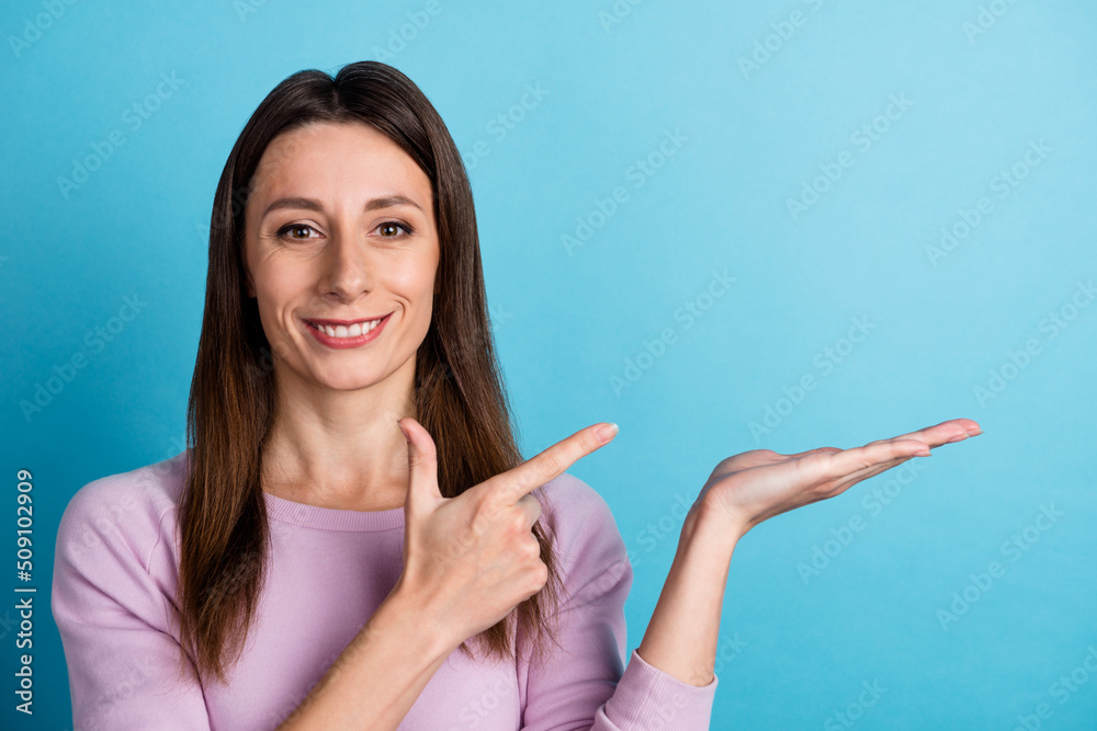 Photo of young lady indicate finger product promotion presentation discount isolated over blue color background Photo of young lady indicate finger product promotion presentation discount isolated over blue color background