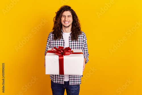 Photo of young cheerful man hold big present surprise holiday event isolated over yellow color background
