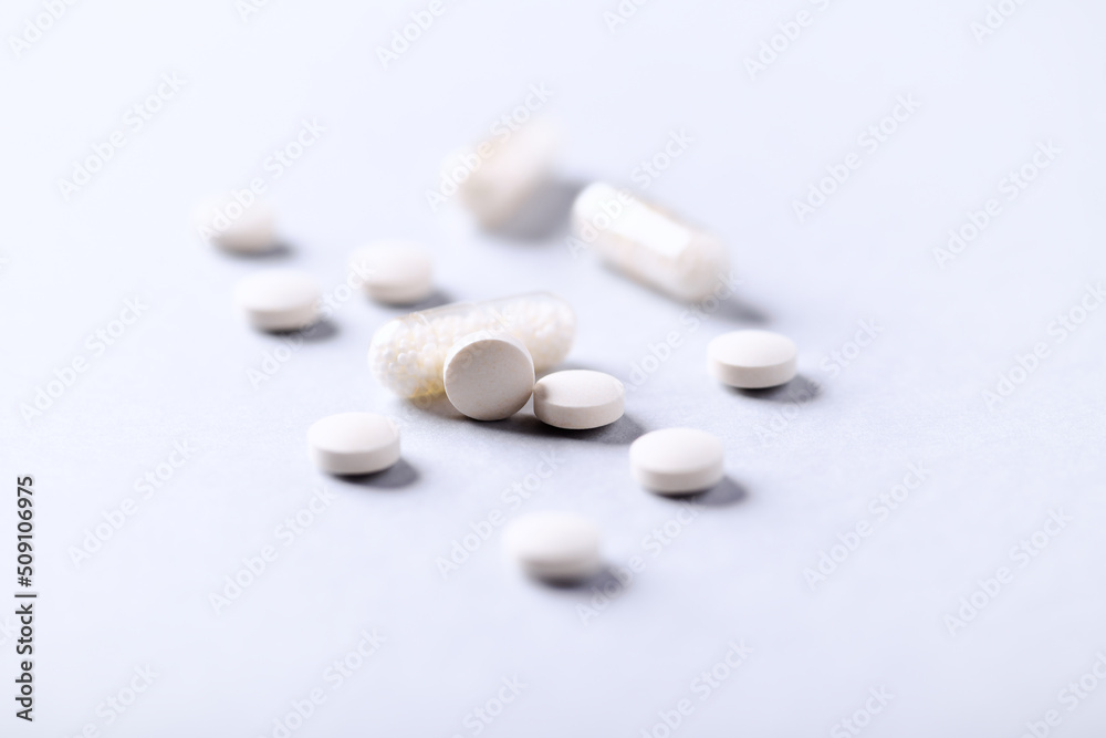 Vitamin C tablets and capsules on bright paper background. Soft focus. Close up. Copy space. Vitamin C tablets and capsules on bright paper background. Soft focus. Close up. Copy space.