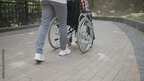 Nurse pushing wheelchair with patient in park, rehabilitation, close-up