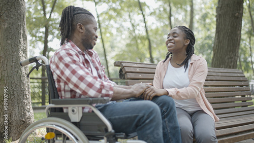 Man in wheelchair having fun on date with a young woman, love, relationship