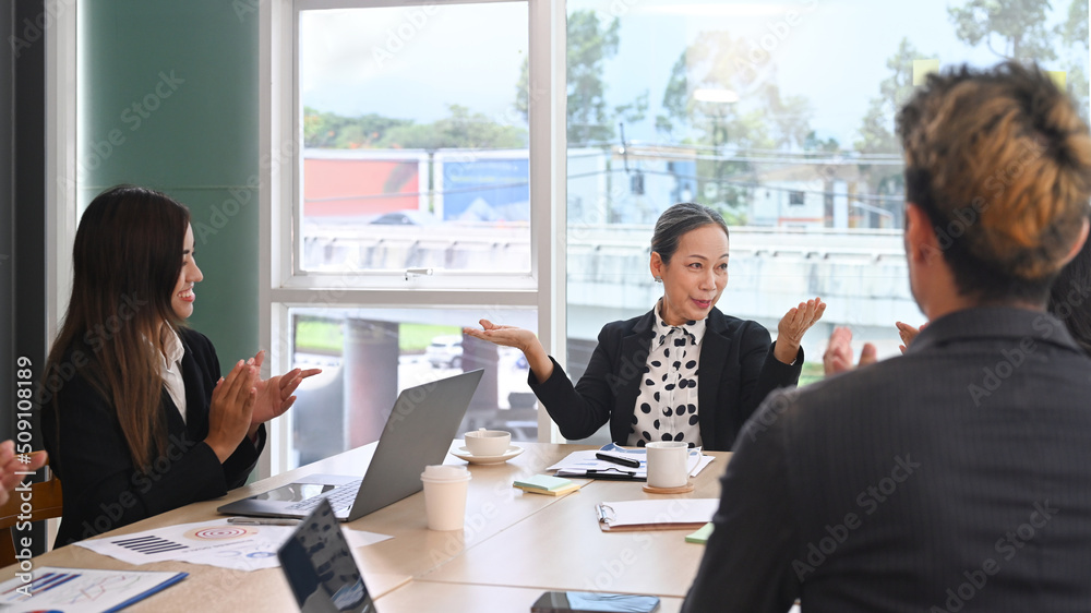 Attractive middle aged female team leader explaining project details, discussing for new strategy of development to diverse employees in meeting Attractive middle aged female team leader explaining project details, discussing for new strategy of development to diverse employees in meeting