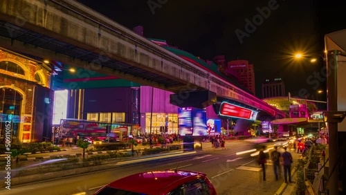 Timelapse of modern Asian city intersection at night. Car light trails, urban lights, ads, people cross streets, monorail train station, Kuala Lumpur photo