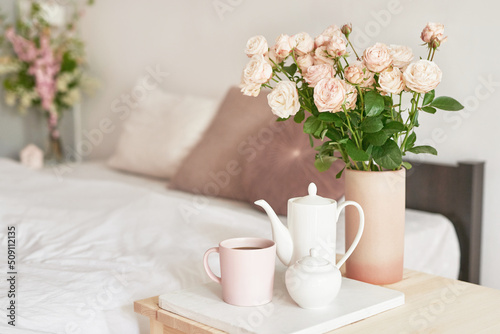 Good cozy morning. Bouquet of rose flowers in vase on table. Hotel room with bed. Check in hotel. Rest and relaxation. Coffee in bed. Romantic breakfast. Valentine's Day