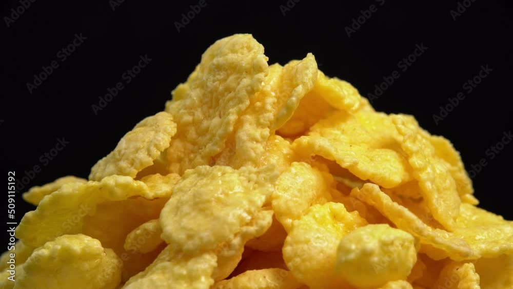 Crispy corn flakes rotating on black background close up, dry healthy breakfast. Honey cornflakes for healthy cereal breakfast. Cooking healthy breakfast concept. High quality 4k footage Crispy corn flakes rotating on black background close up, dry healthy breakfast. Honey cornflakes for healthy cereal breakfast. Cooking healthy breakfast concept. High quality 4k footage