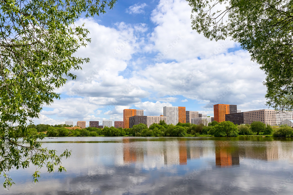 New modern residential apartment buildings district  near the lake surrounded by green trees and grass	