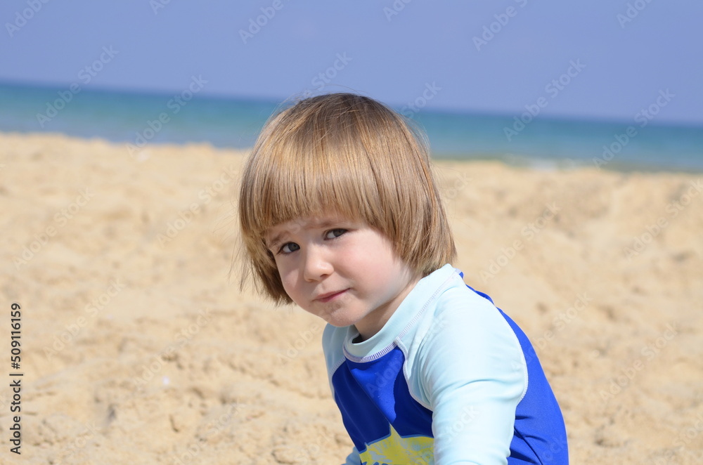 A little boy in a bathing suit on the beach. Space for text. Concept: family resort, family trip, swimming school A little boy in a bathing suit on the beach. Space for text. Concept: family resort, family trip, swimming school