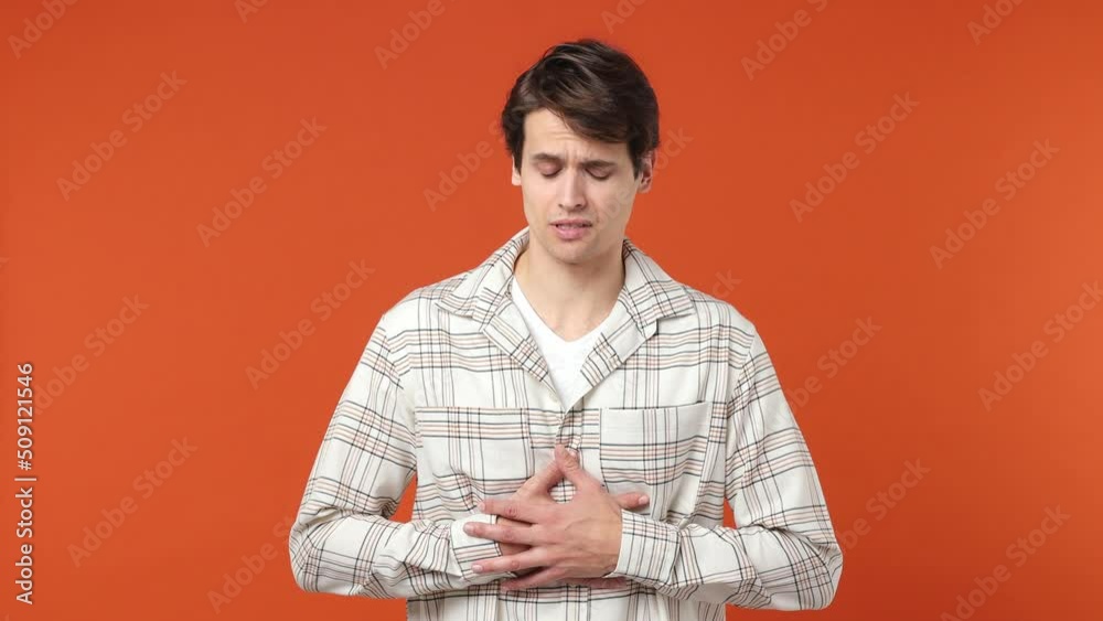 Sick ill young brunette man 20s years old wears white shirt put hands on abdomen suffering from stomach-ache griping bellyache feel bad seedy isolated on plain orange wall background studio portrait Sick ill young brunette man 20s years old wears white shirt put hands on abdomen suffering from stomach-ache griping bellyache feel bad seedy isolated on plain orange wall background studio portrait