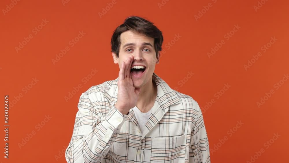 Smiling young brunet man 20s years old wears white shirt look around for friend find waving meet greet with hand scream as notices someone isolated on plain orange wall background studio portrait Smiling young brunet man 20s years old wears white shirt look around for friend find waving meet greet with hand scream as notices someone isolated on plain orange wall background studio portrait