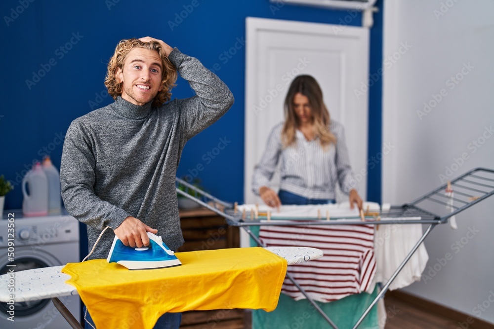 Obraz premium Couple ironing clothes at laundry room stressed and frustrated with hand on head, surprised and angry face