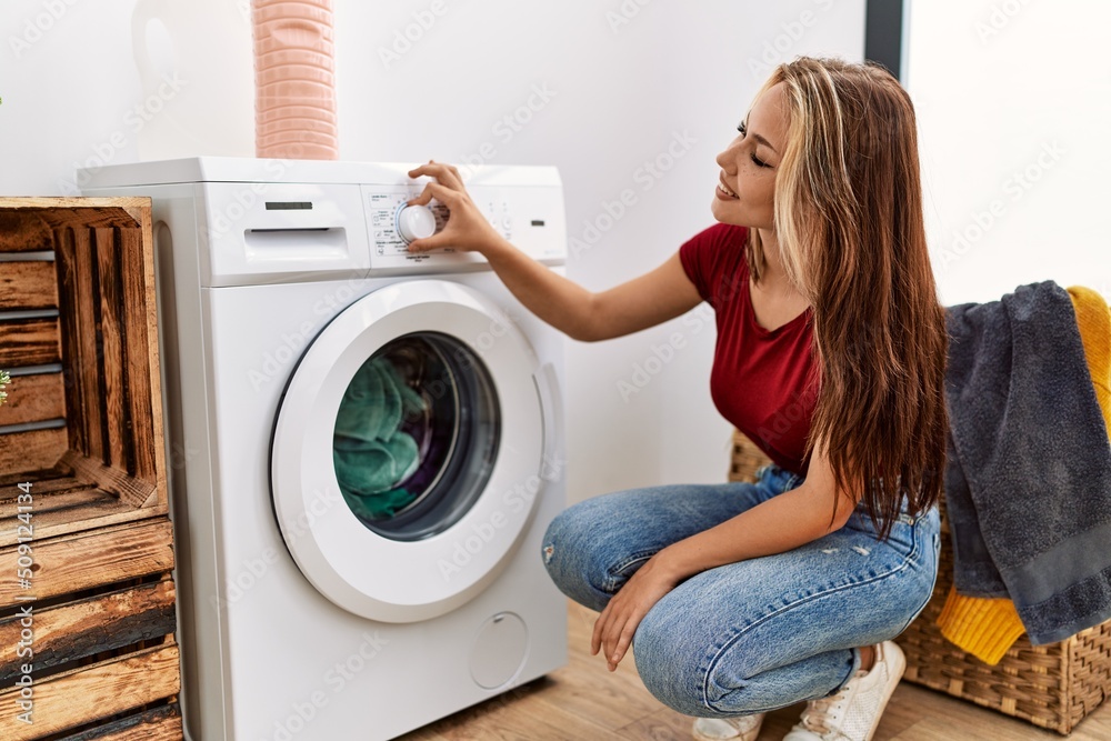 Young caucasian girl smiling happy cleaning clothes using whasing machine at home. Young caucasian girl smiling happy cleaning clothes using whasing machine at home.