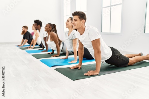 Group of young people smiling happy training yoga at sport center.
