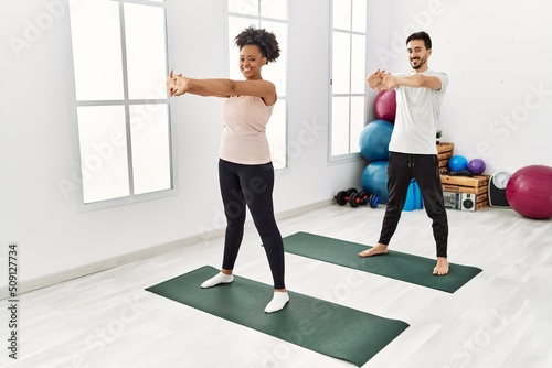 Young african american woman and hispanic man exercising at pilates room  stretching body and doing yoga pose  training strength and balance