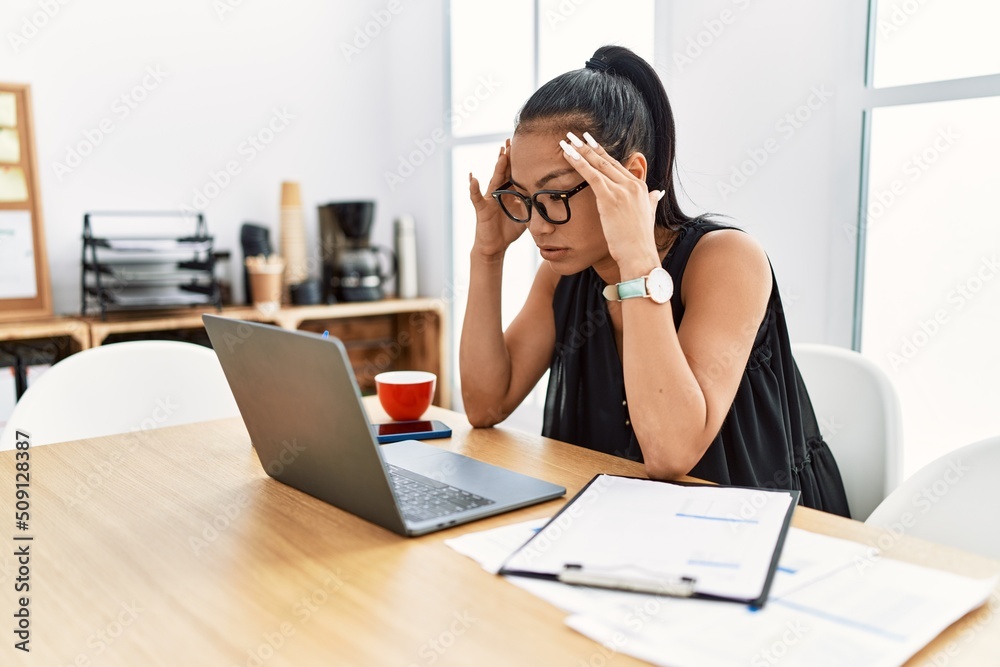Young latin woman stressed working at office