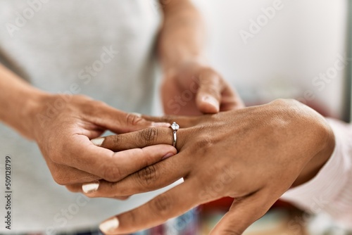 Hands of ouple on marriage proposal at the bedroom. Man putting engagement ring on woman finger.