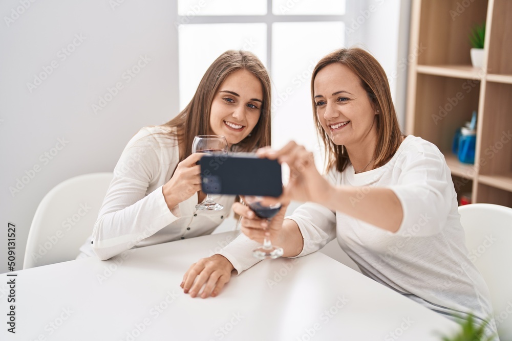 Two women mother and daughter drinking glass of wine make selfie by smartphone at home Two women mother and daughter drinking glass of wine make selfie by smartphone at home