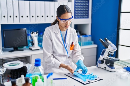 Young african american woman scientist wearing gloves at laboratory