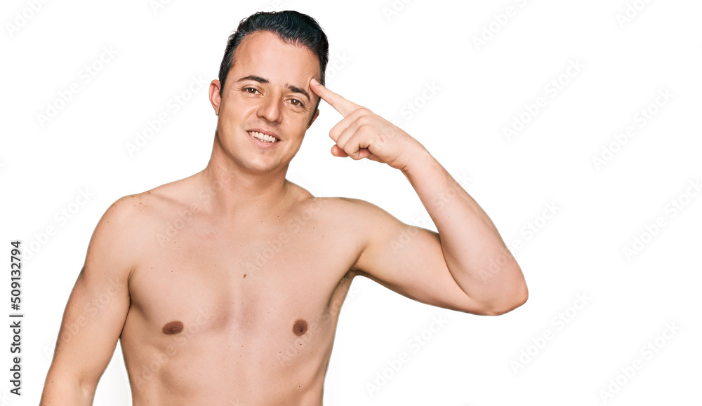 Handsome young man wearing swimwear shirtless smiling pointing to head with one finger, great idea or thought, good memory