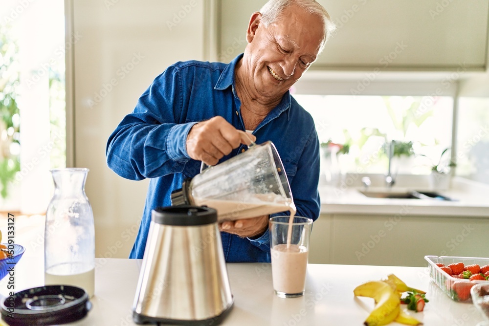 Senior man smiling confident pouring smoothie on glass at kitchen Senior man smiling confident pouring smoothie on glass at kitchen