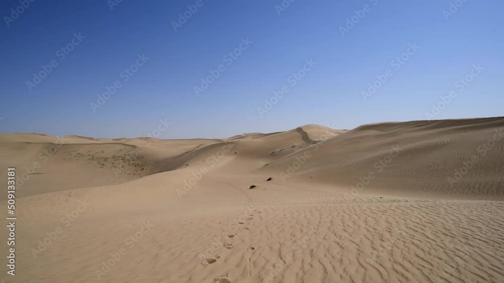 Video that follows footprints in the sand surrounded by beautiful dunes and incredible blue skies in the majestic Middle Eastern desert in the Arabian Peninsula. Desert landscape with copy space Video that follows footprints in the sand surrounded by beautiful dunes and incredible blue skies in the majestic Middle Eastern desert in the Arabian Peninsula. Desert landscape with copy space