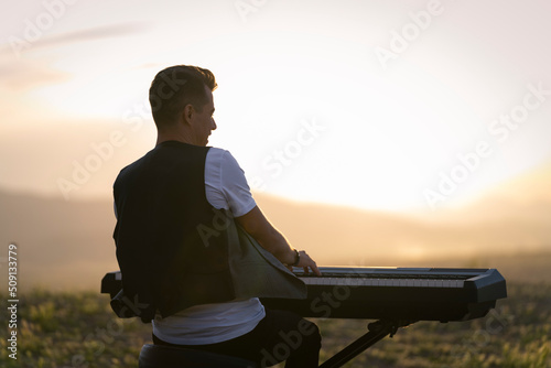 Pianist playing the piano at sunset in a park