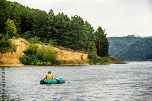 a lonely fisherman on the boat in the middle of the Dnister river, Podilski tovtry National park, Ukraine