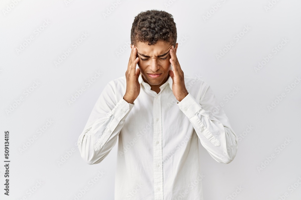 Young handsome hispanic man standing over isolated background with hand on head for pain in head because stress. suffering migraine. Young handsome hispanic man standing over isolated background with hand on head for pain in head because stress. suffering migraine.