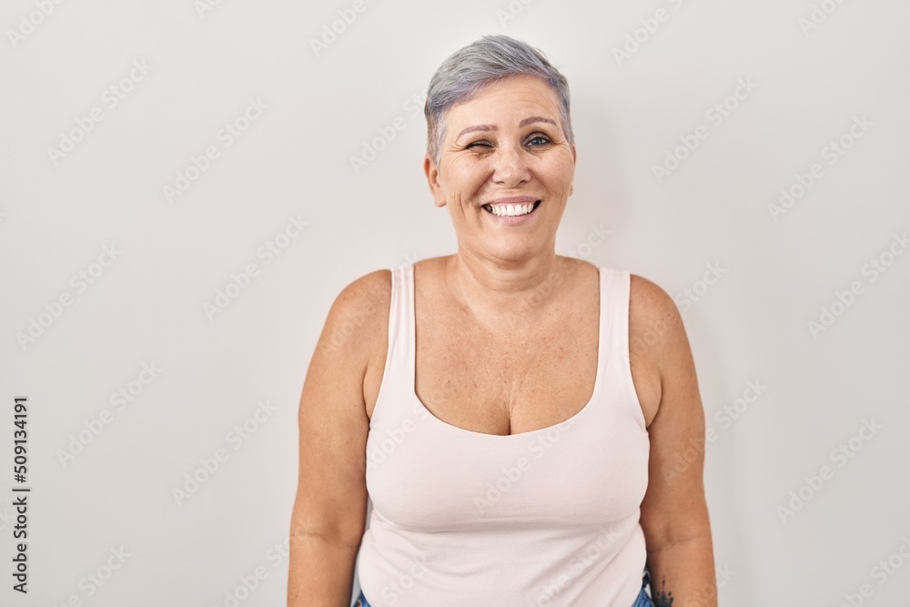 Middle age caucasian woman standing over white background winking looking at the camera with sexy expression, cheerful and happy face. Middle age caucasian woman standing over white background winking looking at the camera with sexy expression, cheerful and happy face.