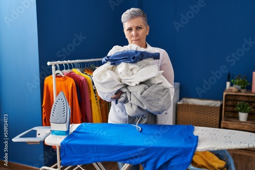 Middle age woman ironing clothes at home skeptic and nervous, frowning upset because of problem. negative person.