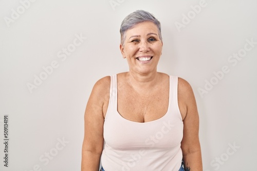 Middle age caucasian woman standing over white background winking looking at the camera with sexy expression, cheerful and happy face.