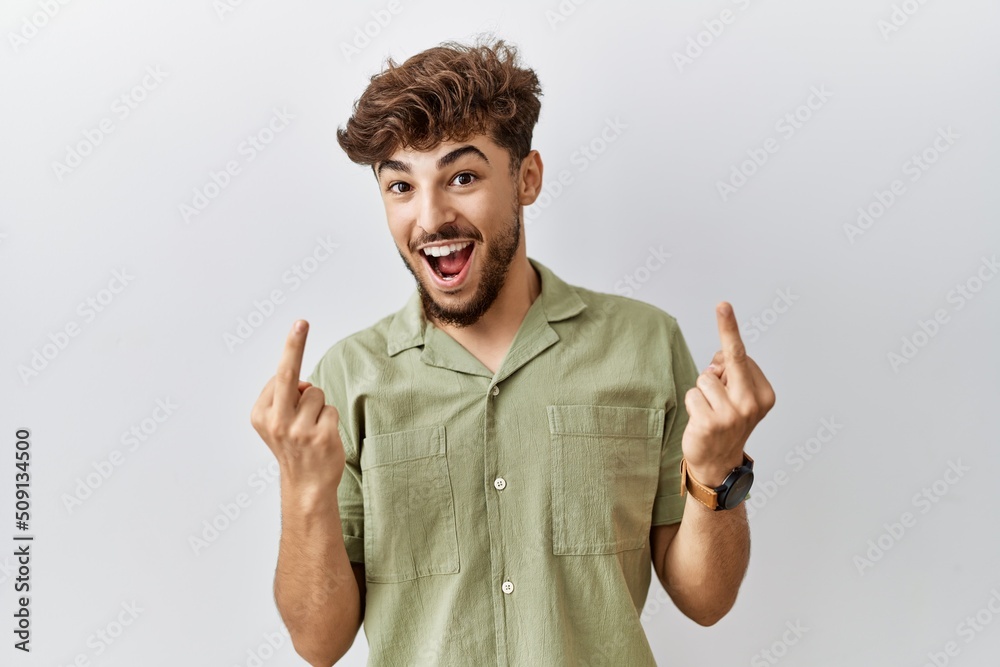 Young arab doctor man standing over isolated background showing middle finger doing fuck you bad expression, provocation and rude attitude. screaming excited Young arab doctor man standing over isolated background showing middle finger doing fuck you bad expression, provocation and rude attitude. screaming excited