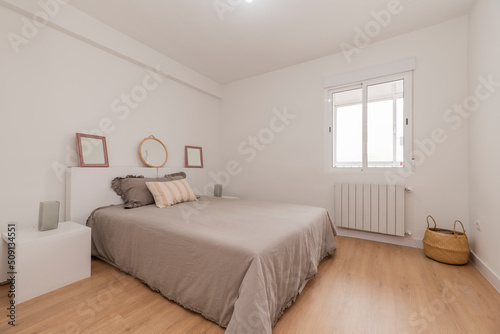 Double bedroom with bed with quilt  white headboard with matching side tables and aluminum window with matching radiator